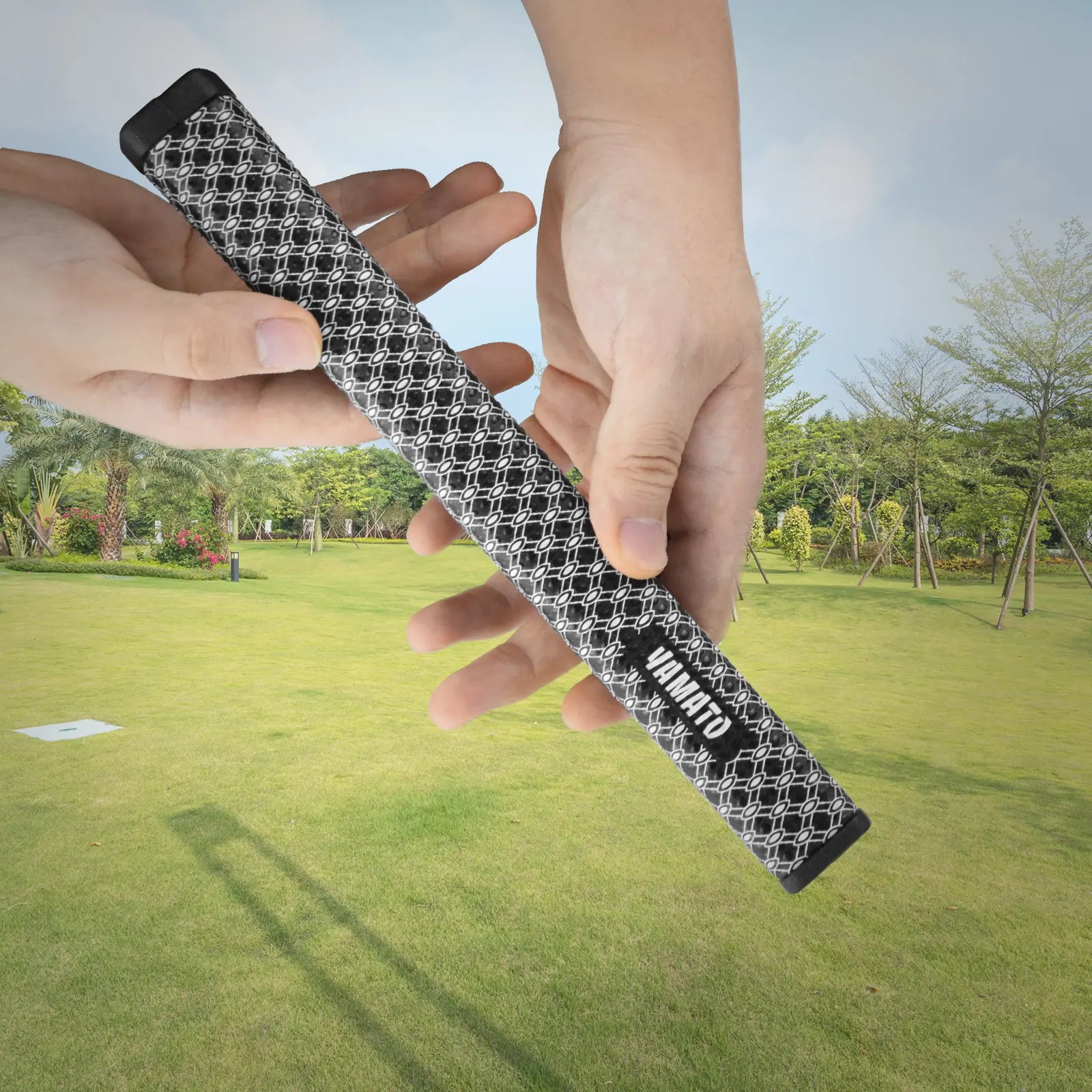 White Yamato golf grip resting on grass with putter