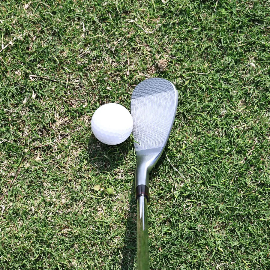 Yamato wedge lying horizontally on turf with golf ball near the clubface